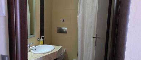 Un baño con lavamanos, inodoro y cortina de ducha.