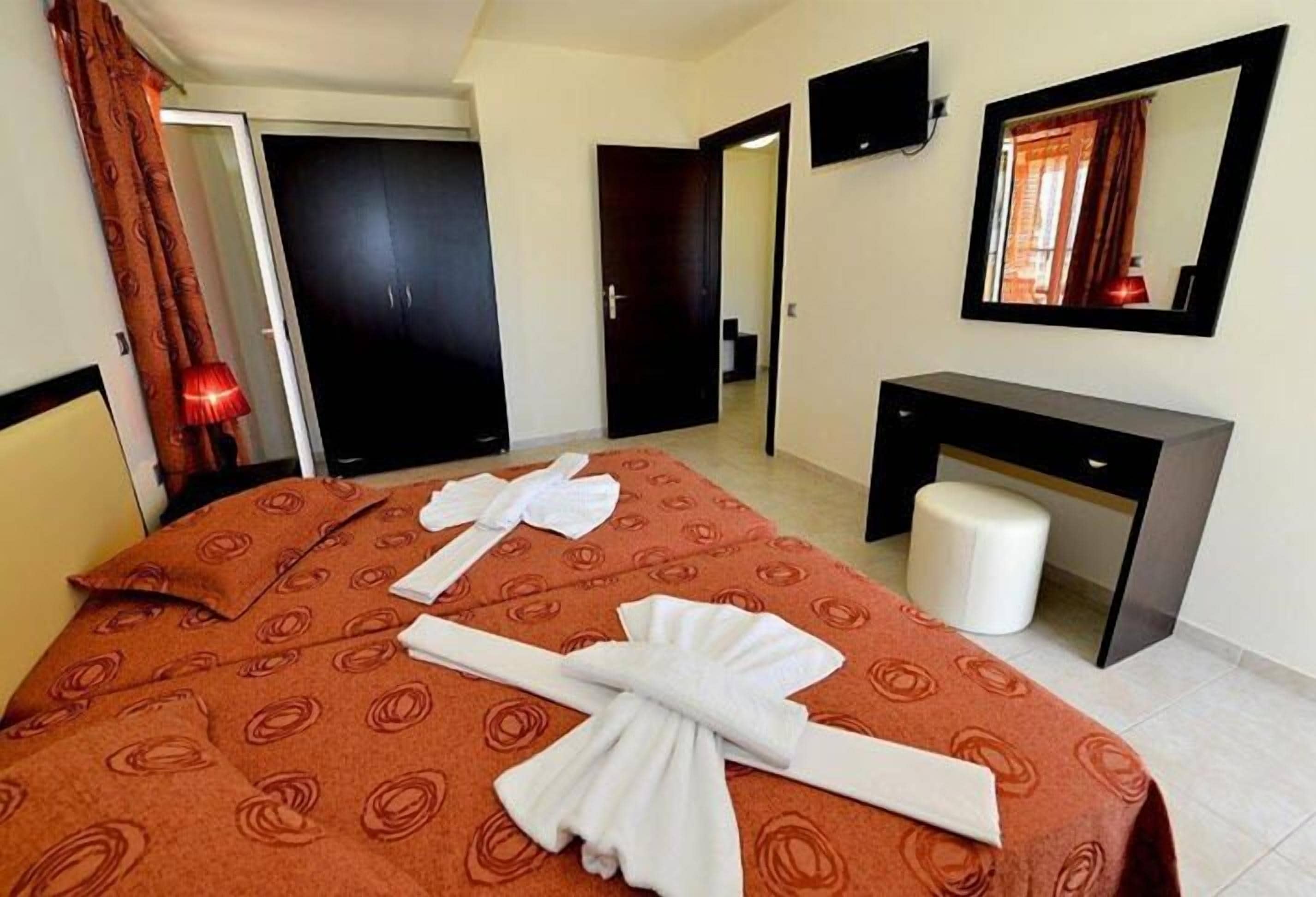 Una camera d'albergo con un letto, una scrivania, uno specchio e una porta.