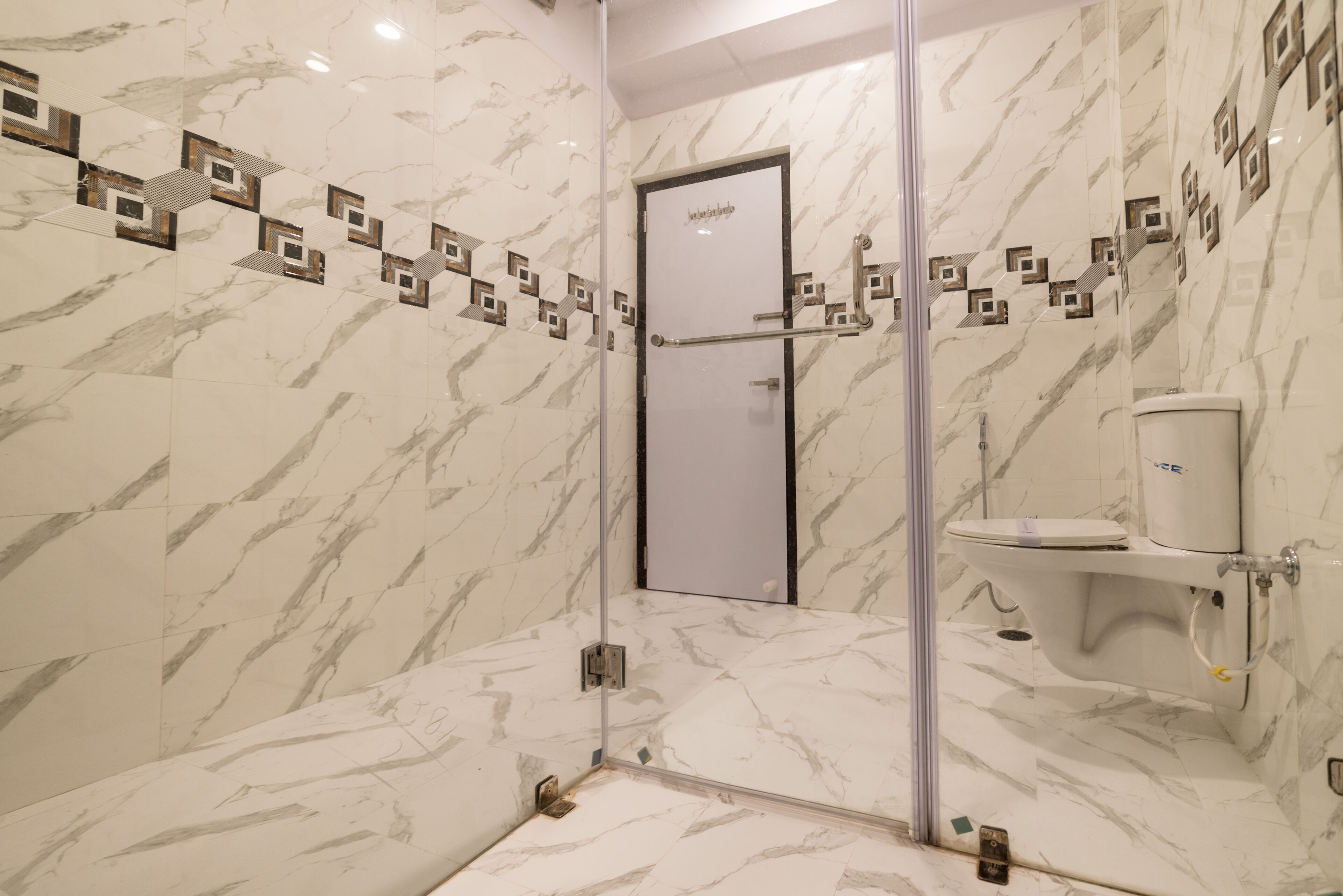 A modern bathroom with marble walls and a glass shower enclosure.