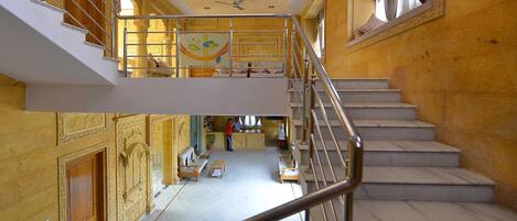 A multi-level interior with a staircase, seating areas, and a reception desk.