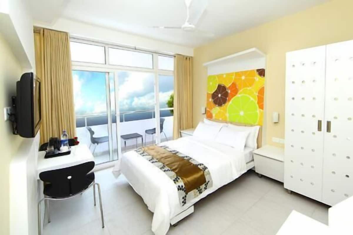 Habitación de hotel con cama, escritorio, silla, armario y un amplio ventanal con vistas.