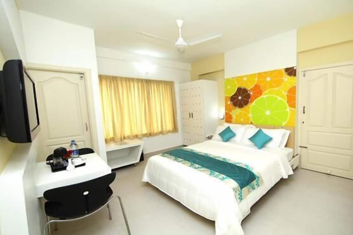 Una habitación de hotel con cama, escritorio, silla, armario y televisor.