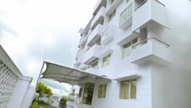 Un edificio blanco de varios pisos con balcones y un acceso cubierto.