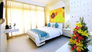Habitación de hotel con una cama, una mesita de noche, un televisor, una ventana con cortinas y un papel tapiz con motivos de frutas.