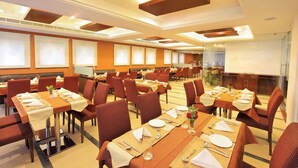 A spacious dining area with multiple tables and chairs, arranged in a modern layout with a central walkway. - Cochin Palace (Kanayannur)