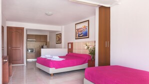 Quarto de hotel com duas camas, uma kitchenette e um banheiro.