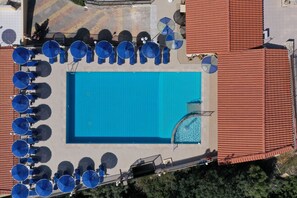Relax by the rectangular pool surrounded by shaded seating areas and lush greenery.