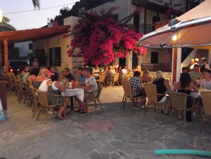 Guests can dine al fresco under a shaded canopy amidst lush surroundings.