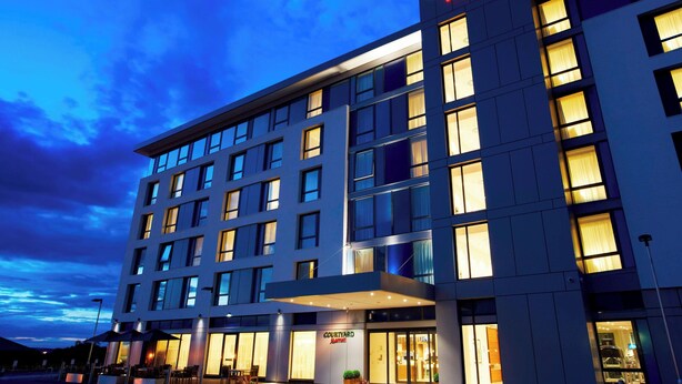 Un hôtel Courtyard Marriott doté d’une façade moderne, de grandes fenêtres et d’une entrée bien éclairée.