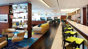 Un hall d’hôtel moderne, doté d’espaces aménagés avec des sièges, d’un bar et d’un comptoir de réception.