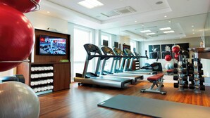 Une salle de sport équipée de tapis de course, de ballons d’exercice et d’un téléviseur fixé au mur.