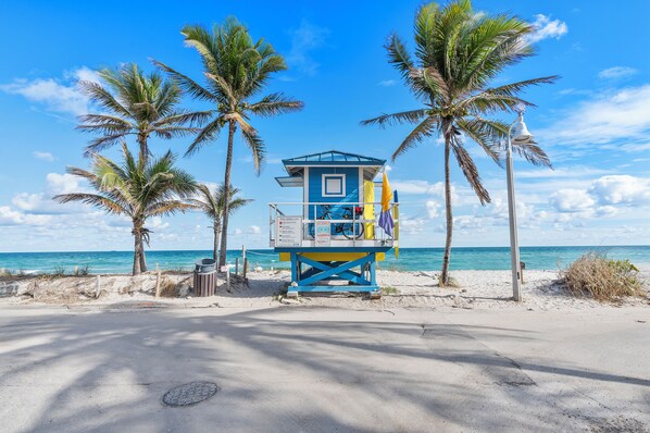 A lifeguard tower on a beach with palm trees and the ocean in the background. - The Desoto Inns (Hollywood)