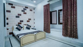 Un dormitorio con cama, aire acondicionado en la pared y cortinas estampadas.