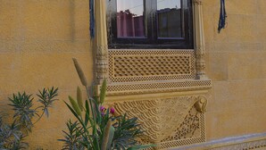 Une fenêtre richement décorée, ornée de sculptures complexes et surmontée d’un arc ornemental.