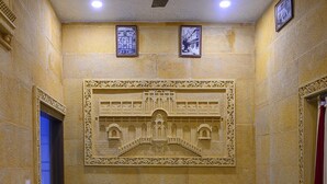 Un couloir doté d’un sol en marbre, d’un ventilateur de plafond et d’une sculpture ornementale sur le mur.