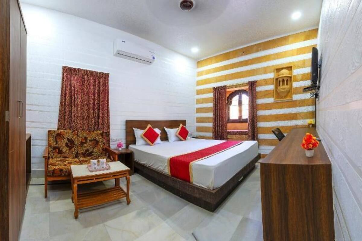 A hotel room with a bed, a wooden chair, a small table, and a TV.