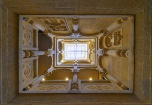A detailed architectural view of a grand hall with ornate columns and a central window. - Hotel Akashdeep (Jaisalmer)