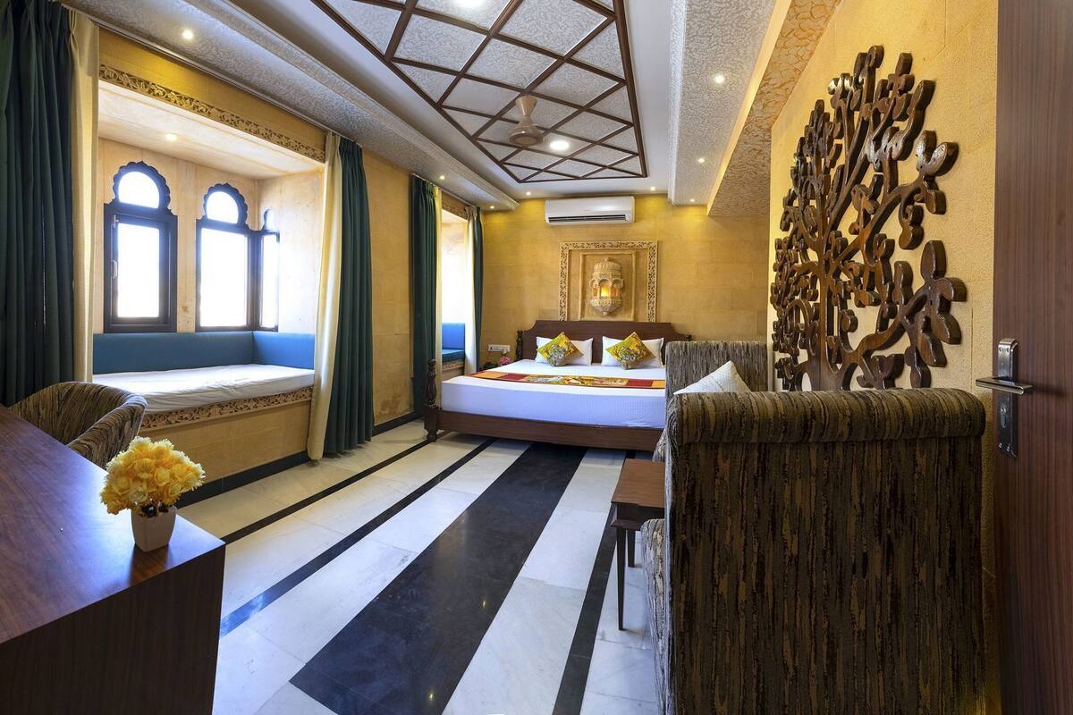 A hotel room with a bed, a seating area with a view, a decorative wall piece, and a ceiling fan.