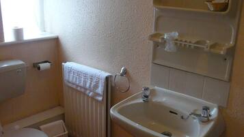 A small bathroom with a toilet, a sink, and a towel rack.