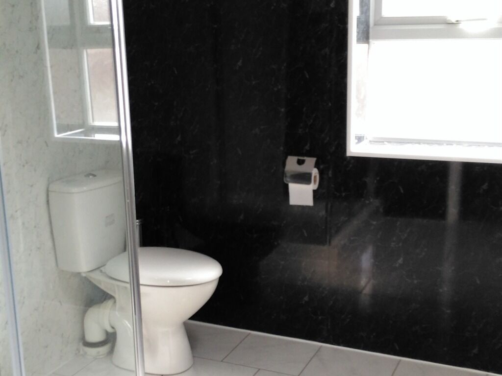 Un bagno con un water bianco, una parete in marmo nero e una finestra che offre luce naturale.