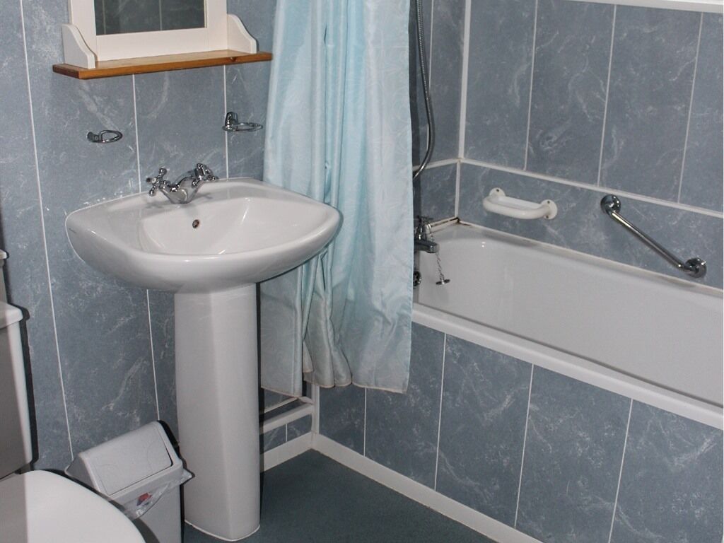 A bathroom with a pedestal sink, a bathtub, and a toilet.