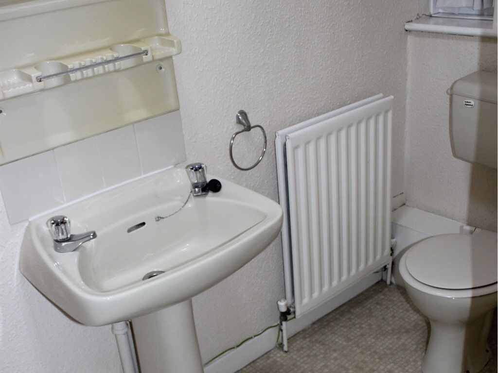 A bathroom with a white sink, toilet, and radiator.