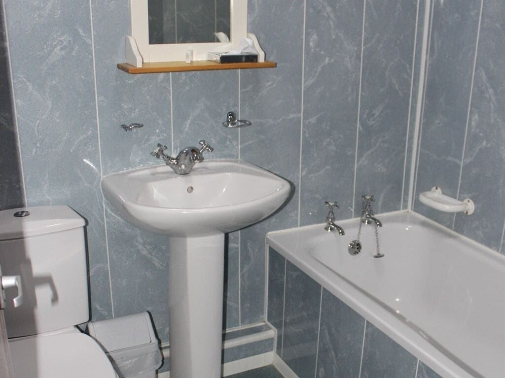A bathroom with a pedestal sink, a bathtub, and a toilet.