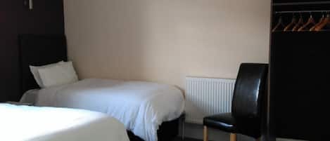 A bedroom with a bed, a chair, a radiator, and a wardrobe.
