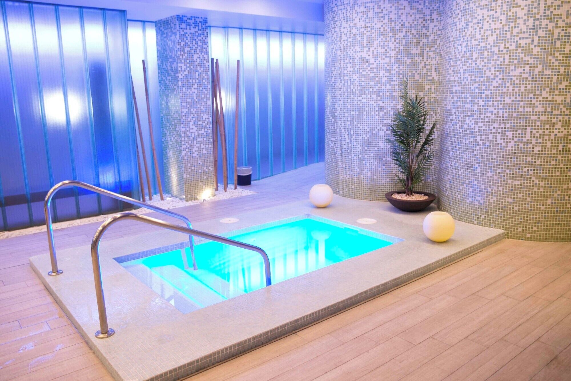 A spa area with a pool, wooden flooring, and tiled walls.