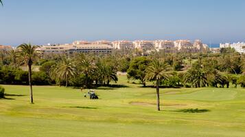 A golf course with a view of a coastal cityscape in the background.