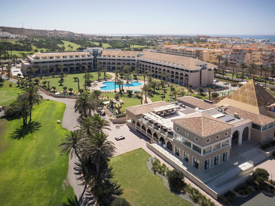 A large hotel with a central courtyard, a swimming pool, and a pyramid-shaped building.