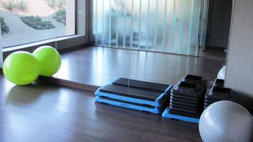 A room with a wooden floor, a step platform, and exercise balls.
