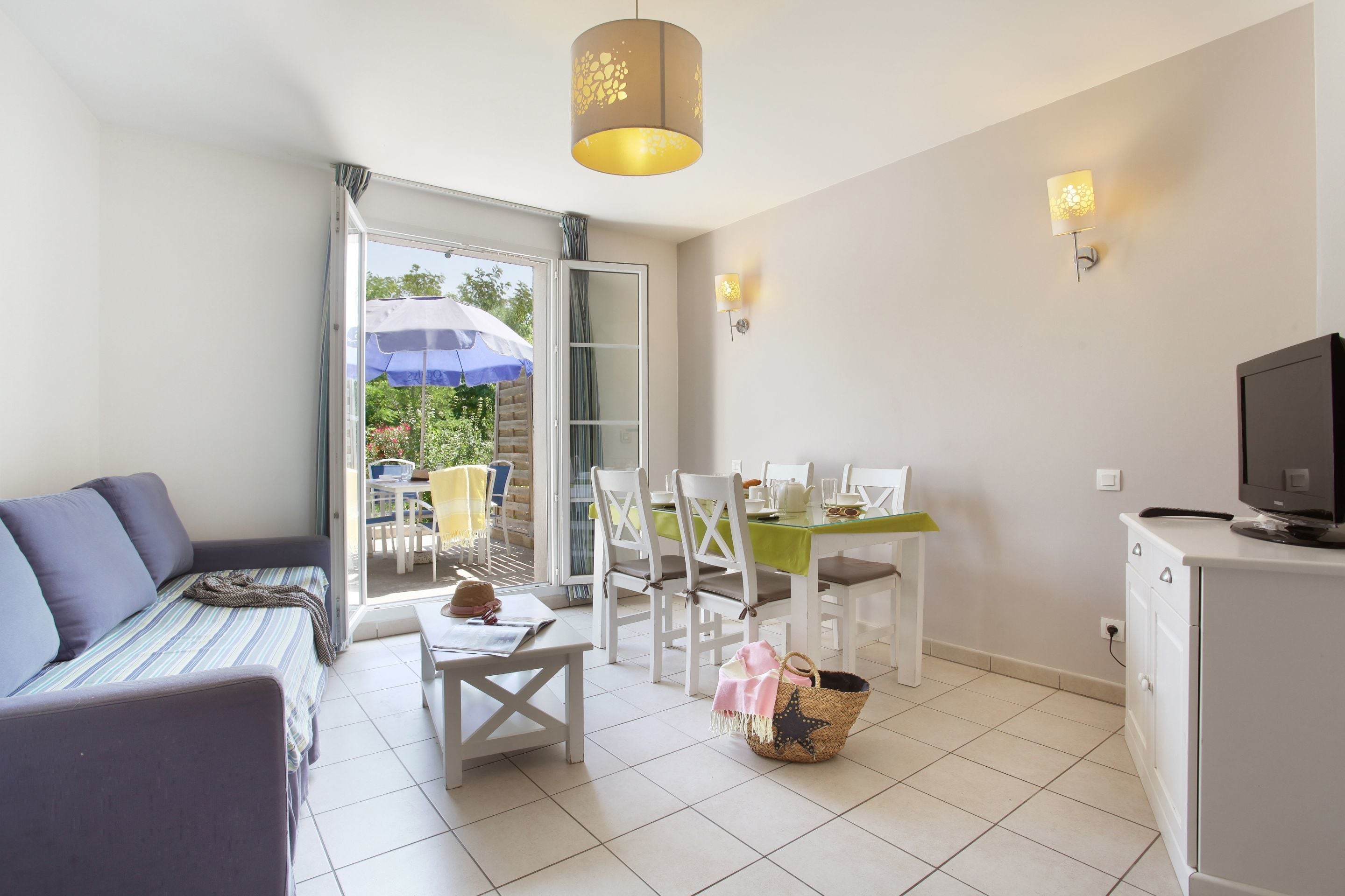 Un salon moderne comprenant un canapé, une table à manger, des chaises et un téléviseur.