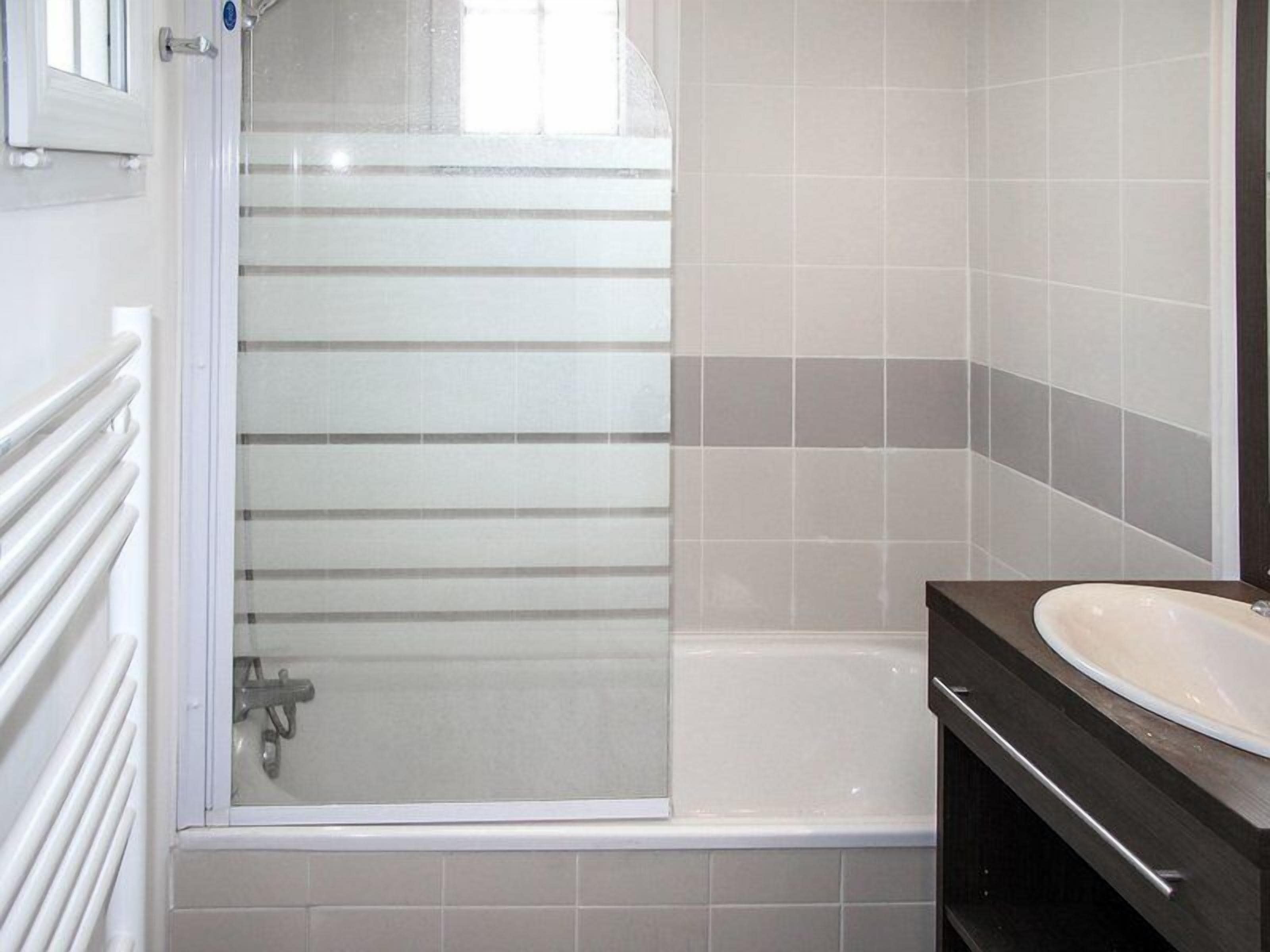 Une salle de bain avec une baignoire, un espace de douche vitré et un meuble-lavabo avec un miroir.