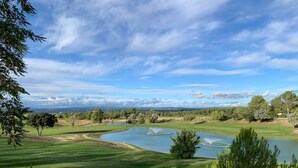Ein Golfplatz mit Teich, Bäumen und blauem Himmel.