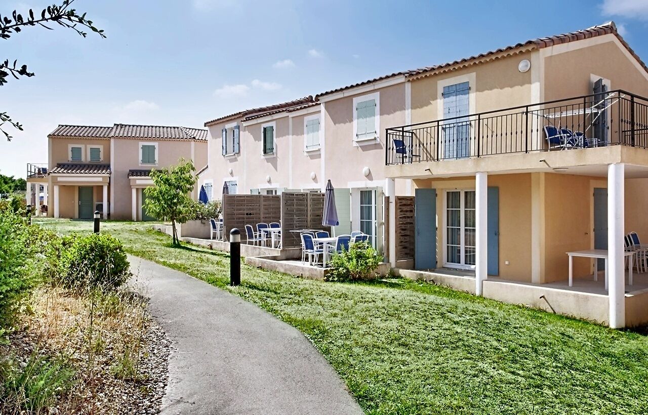 Un immeuble résidentiel doté d’un chemin pavé, d’un espace extérieur aménagé pour s’asseoir et d’un balcon avec une balustrade.