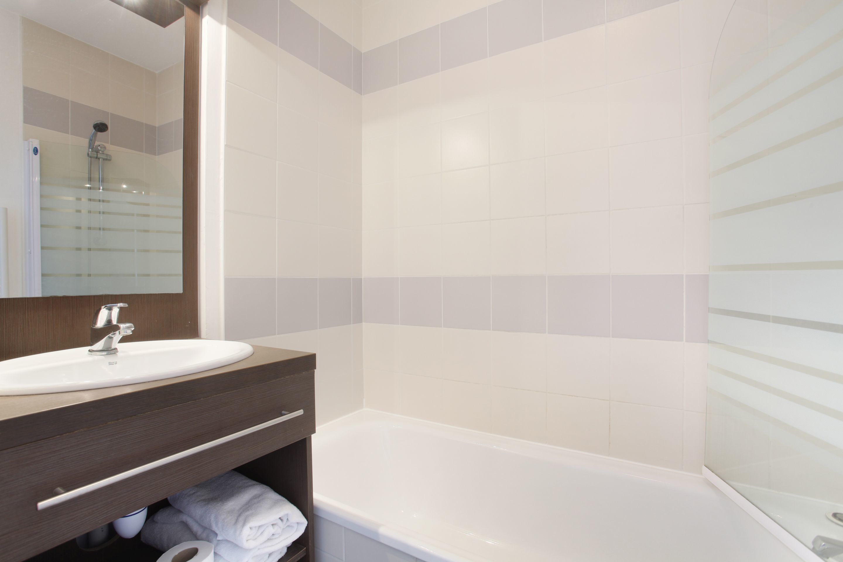 A modern bathroom with a white sink, a mirror, and a bathtub.