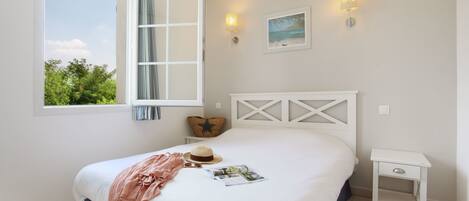 A bedroom with a bed, a nightstand, a window, and wall-mounted lights.
