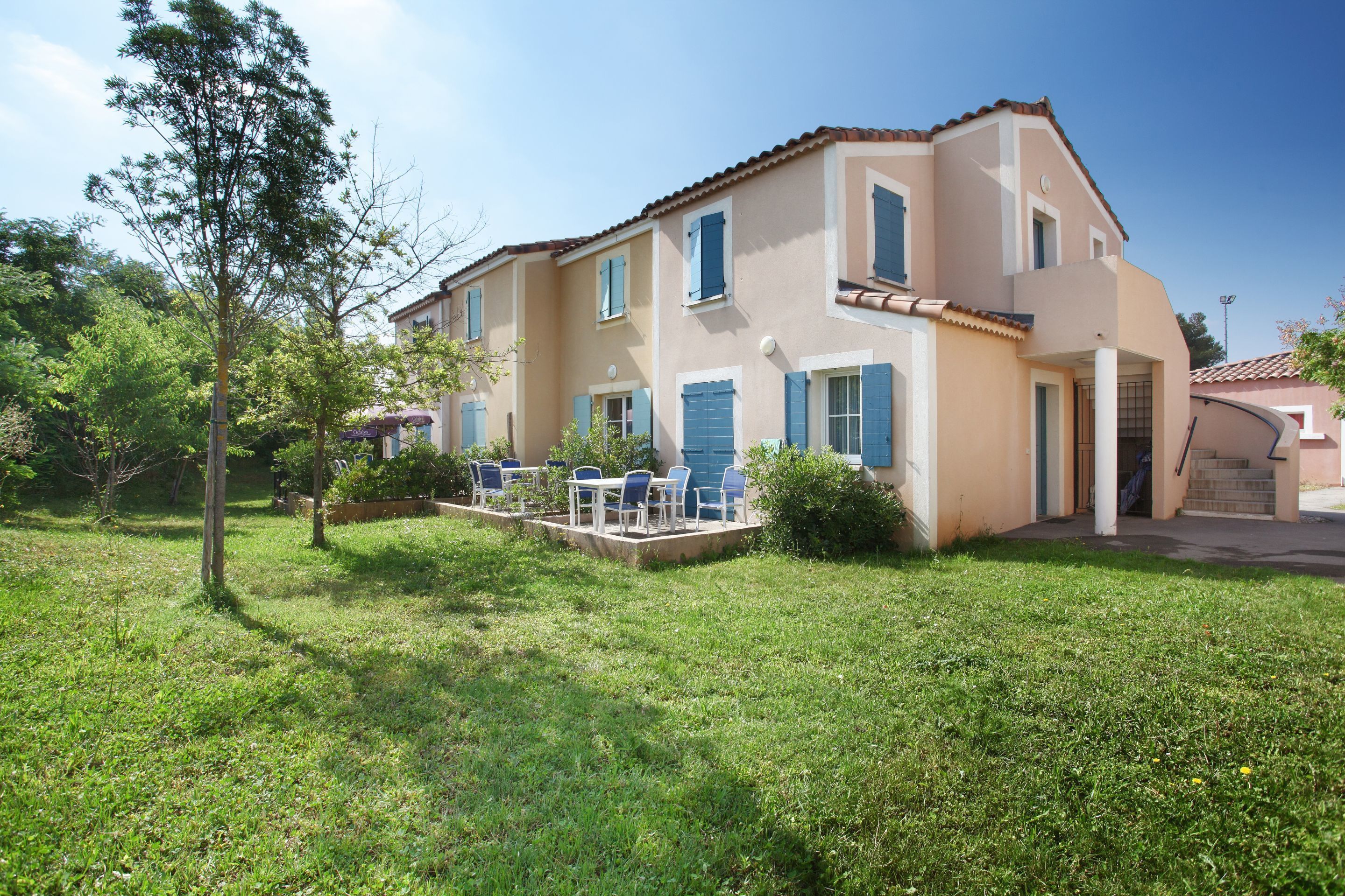 Une maison à deux étages dotée d’un patio et d’un espace extérieur aménagé pour s’asseoir.