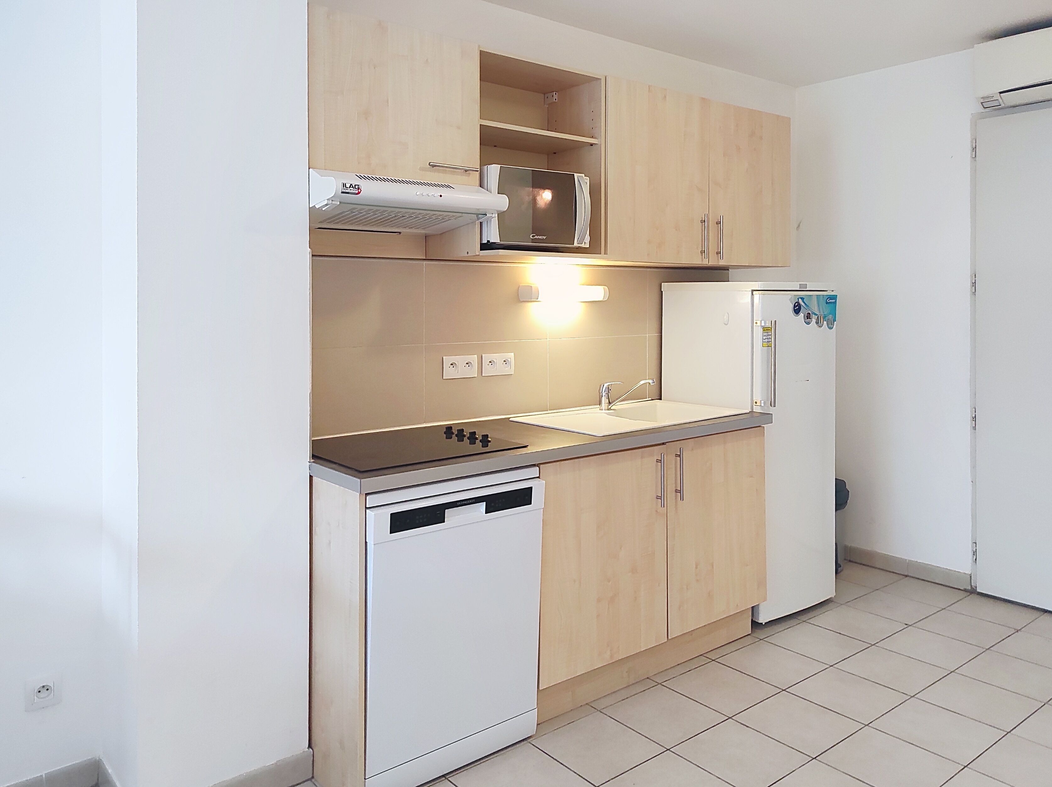 Een keuken met een magnetron, fornuis, spoelbak en koelkast.