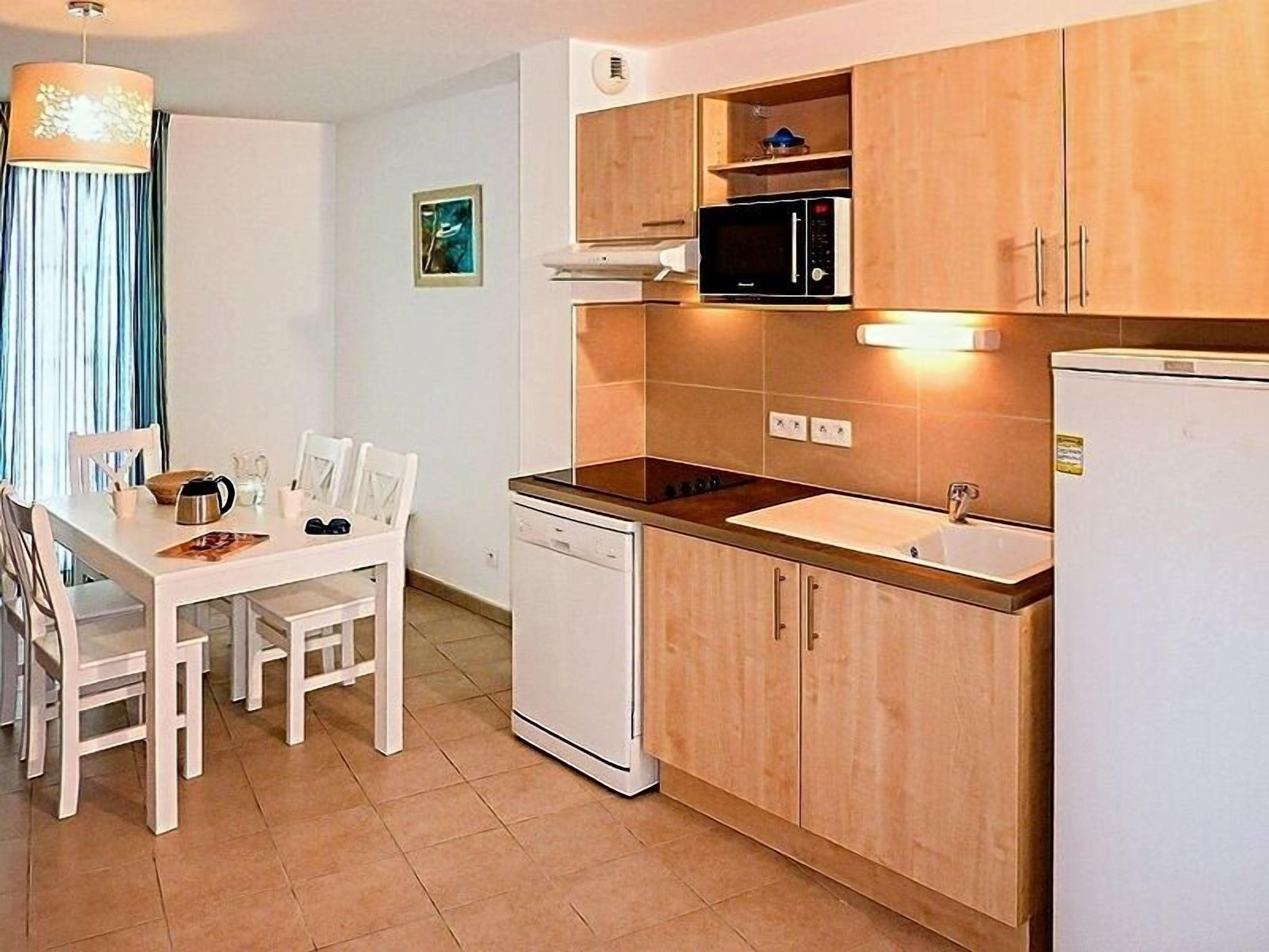 A compact kitchen with a dishwasher, microwave, and a sink.