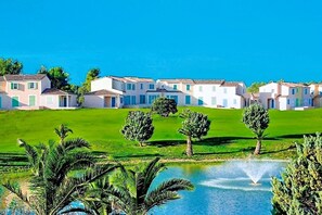 A row of white buildings with flat roofs, a green lawn, and a small pond with a fountain. - Terres de France - Résidence de la Cabre d'Or (Cabries)