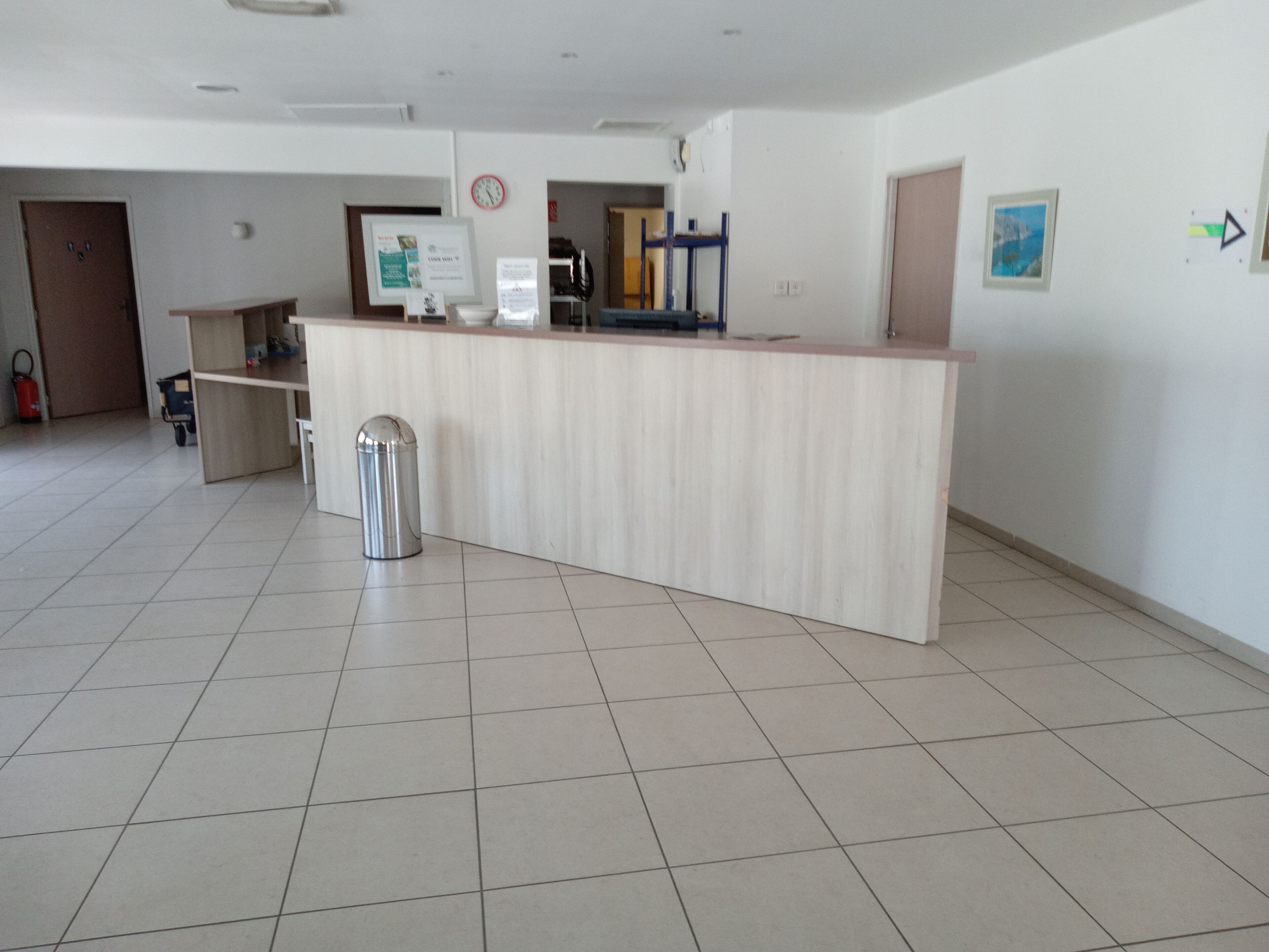 Un'area reception con un banco, un cestino, una sveglia e una porta.