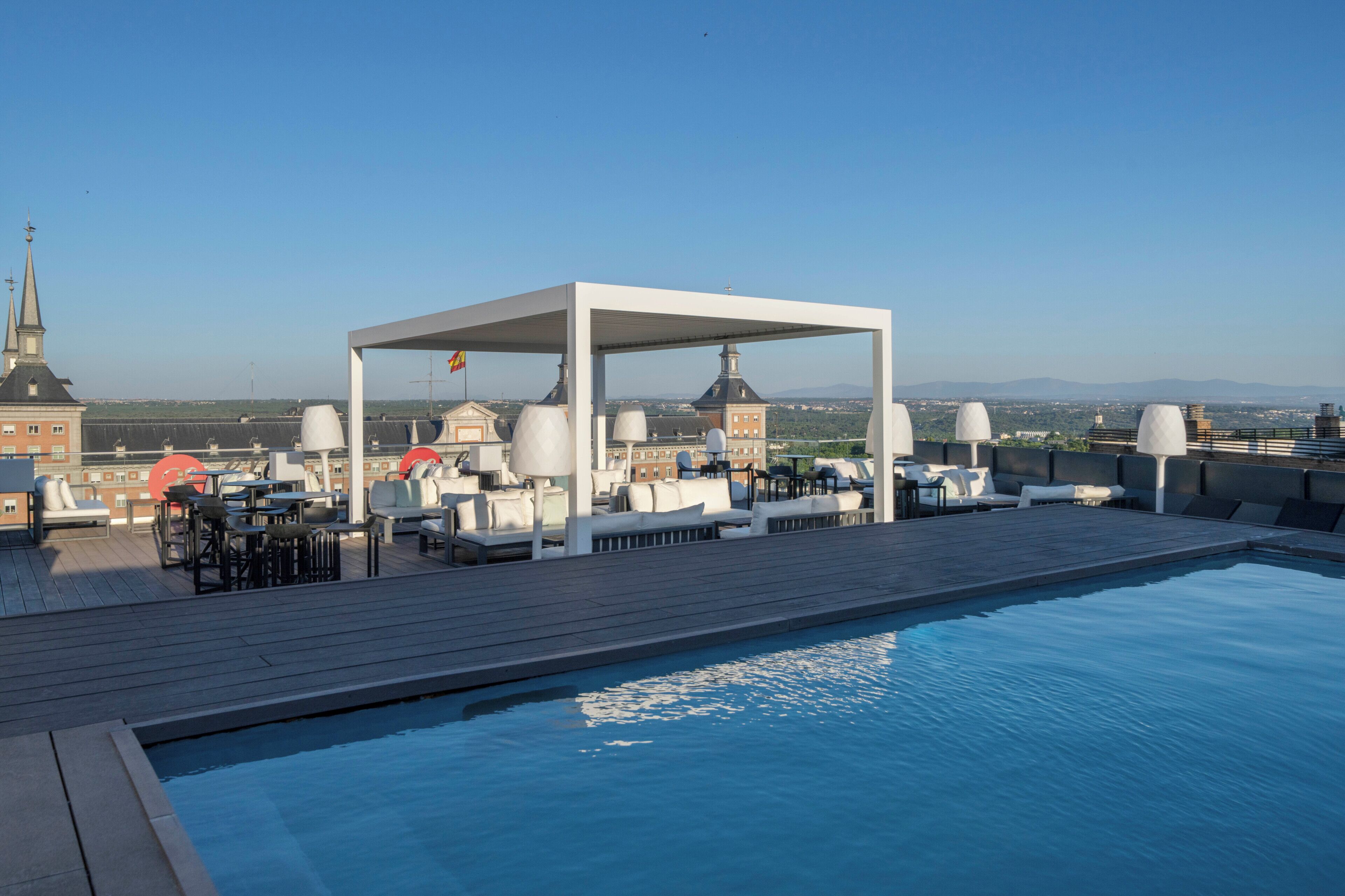 A rooftop pool area with lounge seating and a covered seating area.