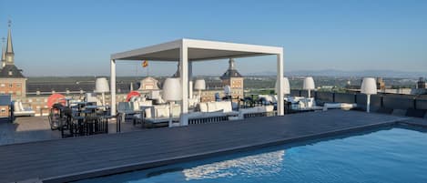 Un espace piscine sur le toit, avec des chaises longues et un coin salon abrité.