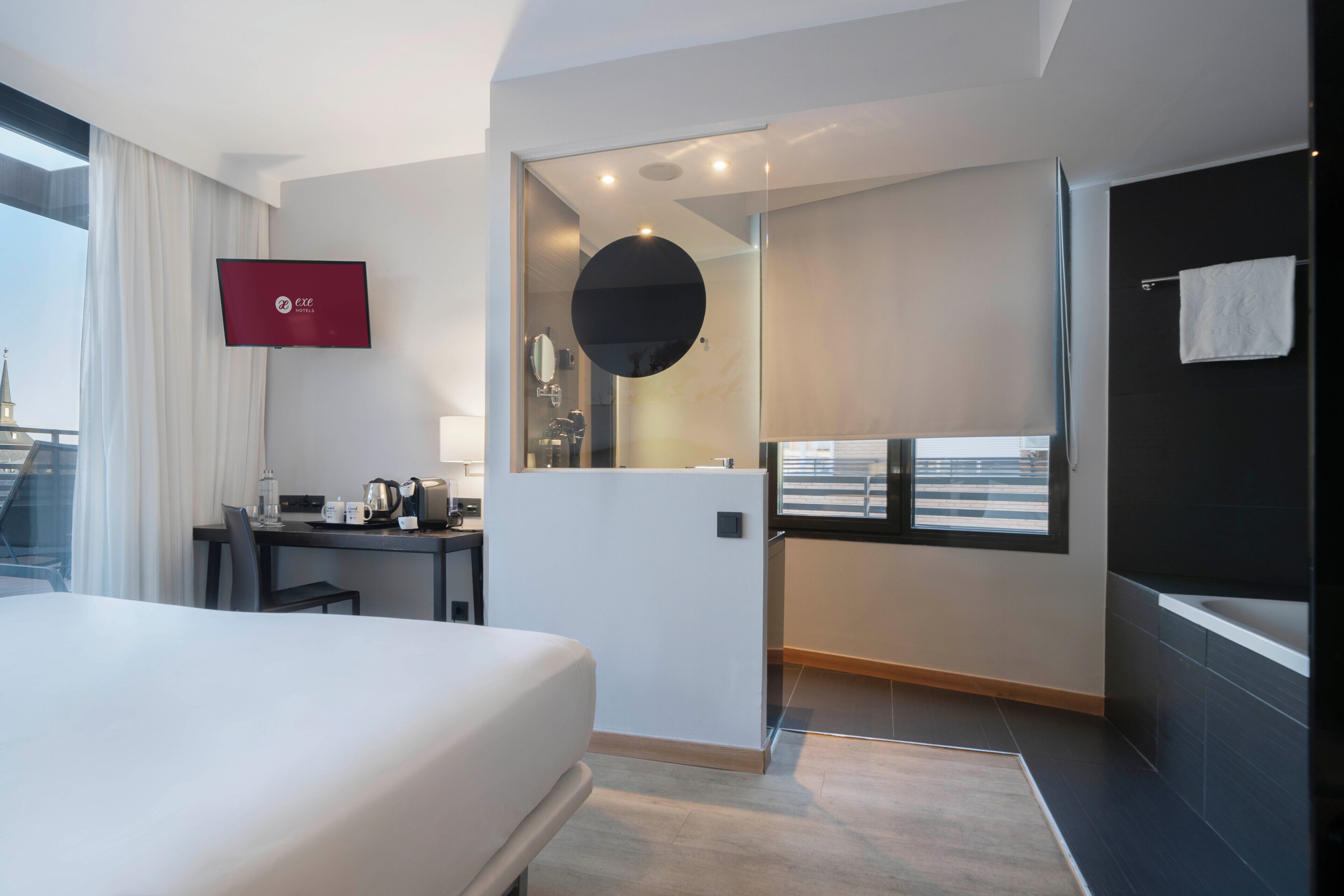 Ein Hotelzimmer mit Bett, Schreibtisch und Blick auf die Stadt.