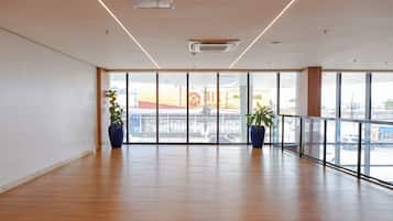 Una habitación espaciosa con amplios ventanales, suelo de madera y dos plantas en macetas.