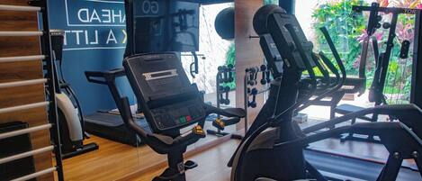 Un gimnasio con equipo de ejercicio, una cinta de correr y una pared con el texto 'HEAD'.