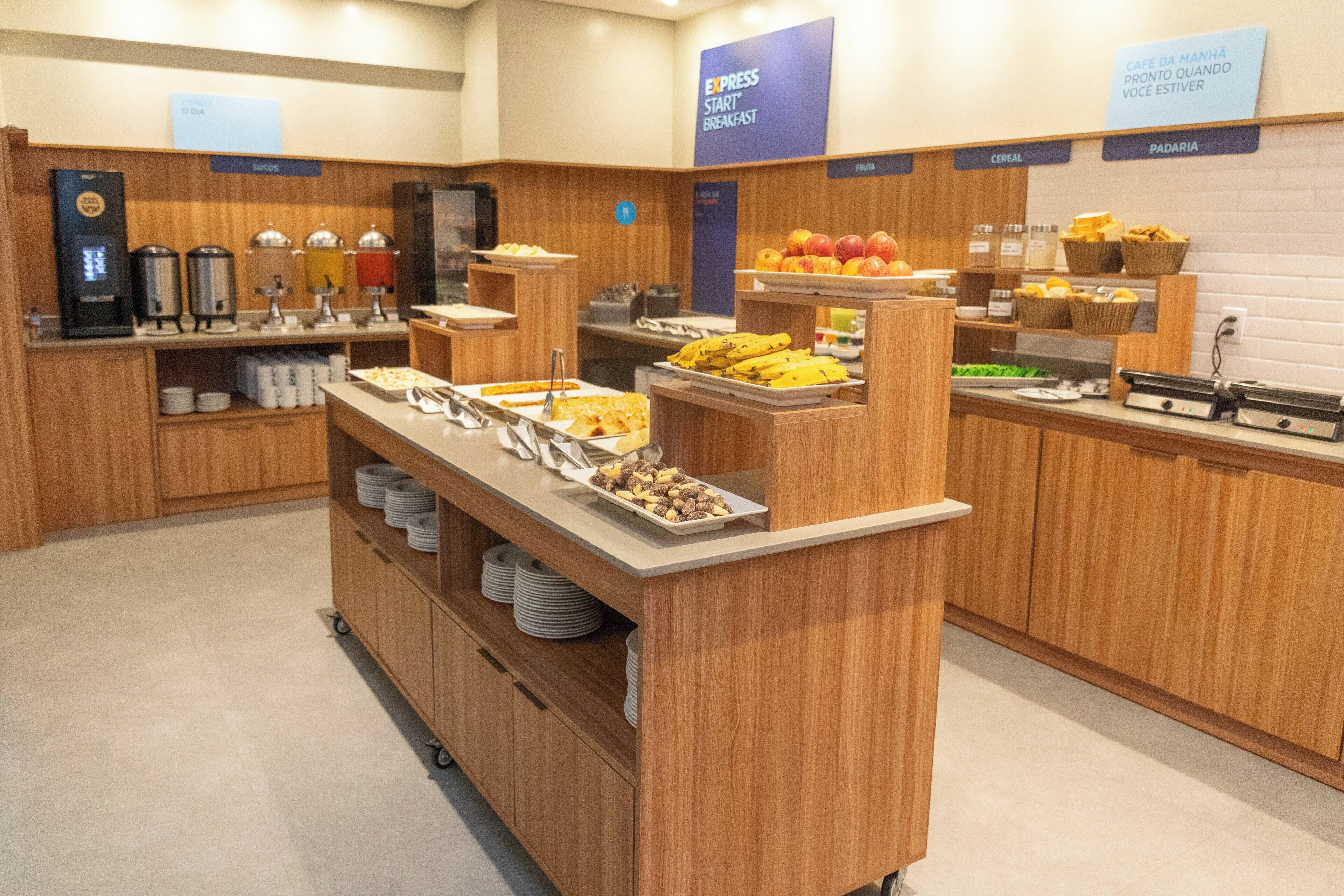 A buffet area with various food stations, including fruits, cereals, and a coffee machine.