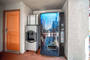 Un pasillo con una puerta, una máquina expendedora y un refrigerador con un atractivo diseño.